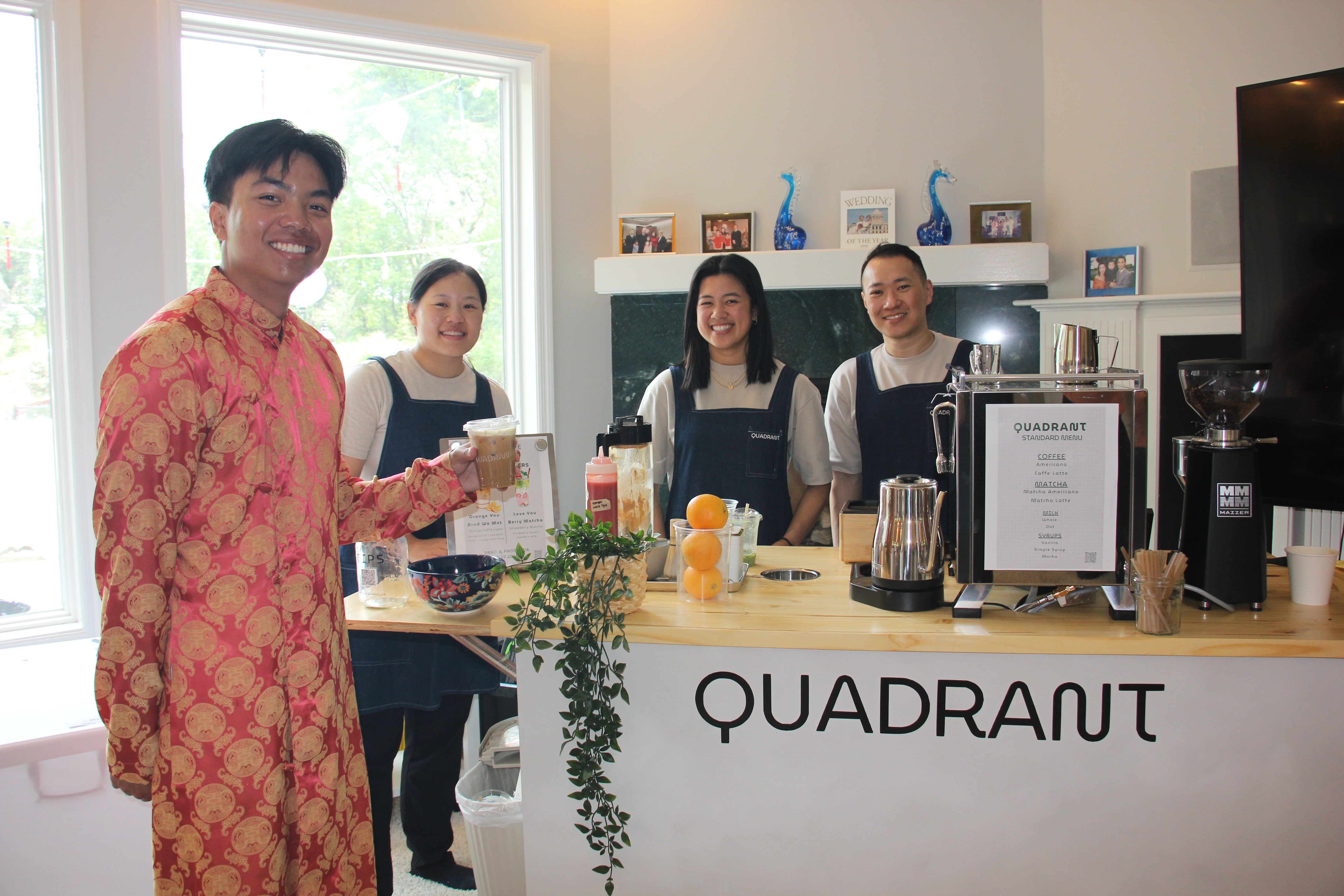 Celebration guest holding an iced coffee in front of the Quadrant Cart team